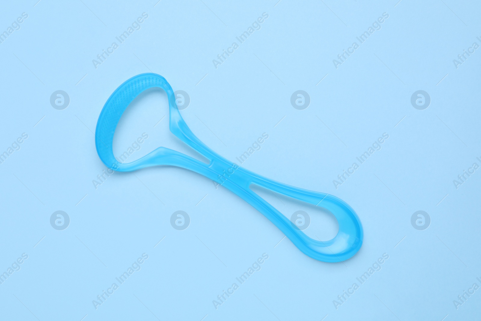 Photo of Tongue cleaner on light blue background, top view