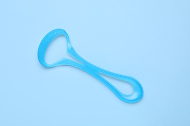 Photo of Tongue cleaner on light blue background, top view