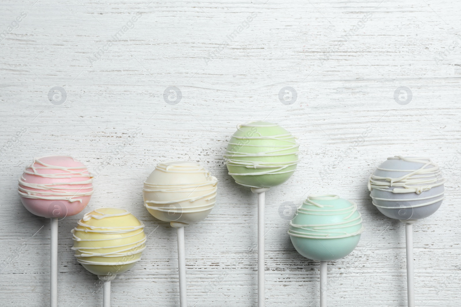 Photo of Sweet cake pops on white wooden background, flat lay. Space for text