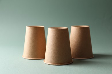 Three paper cups on pale olive background. Thimblerig game