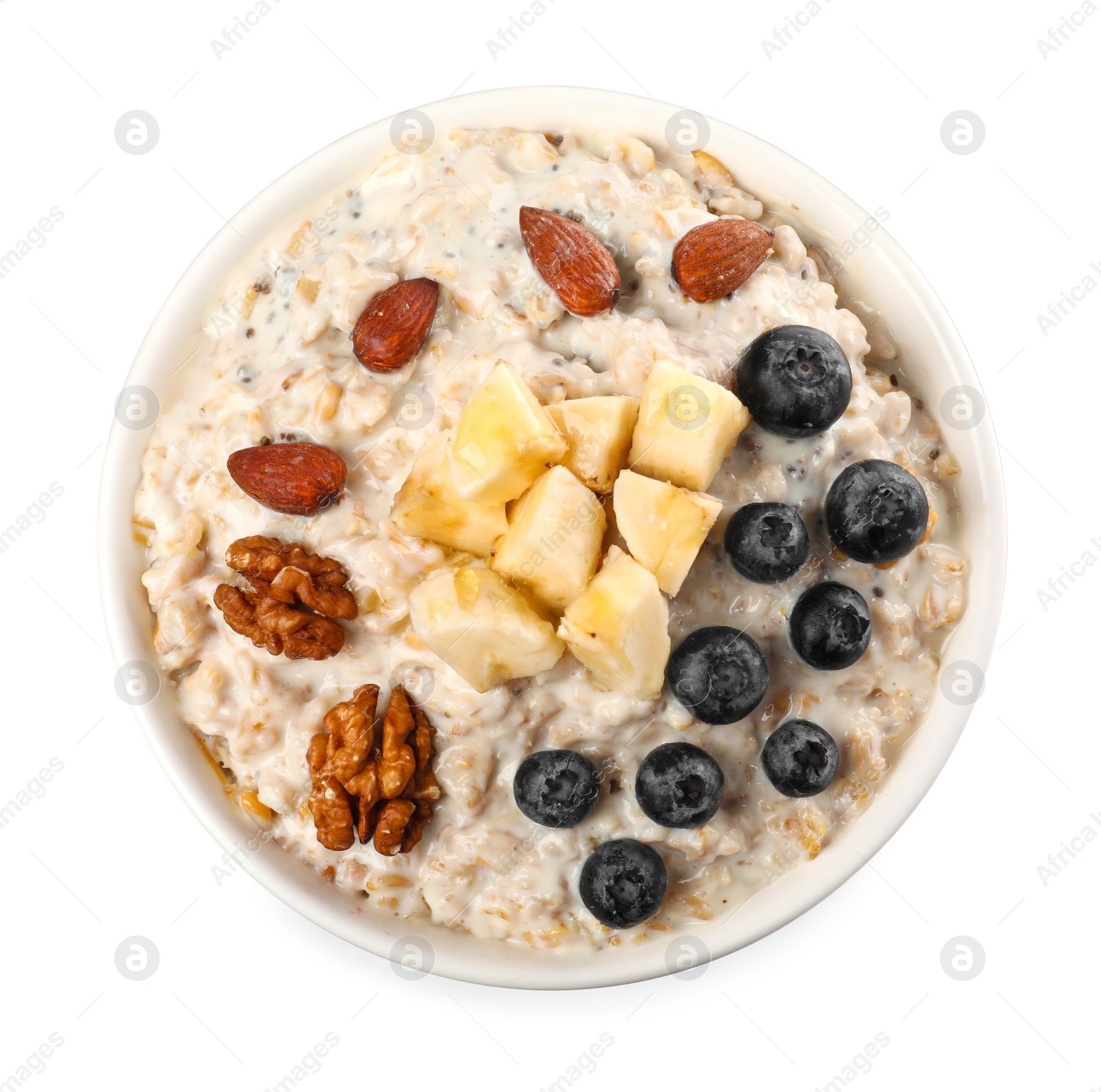 Photo of Tasty boiled oatmeal with blueberries, banana and nuts in bowl isolated on white, top view