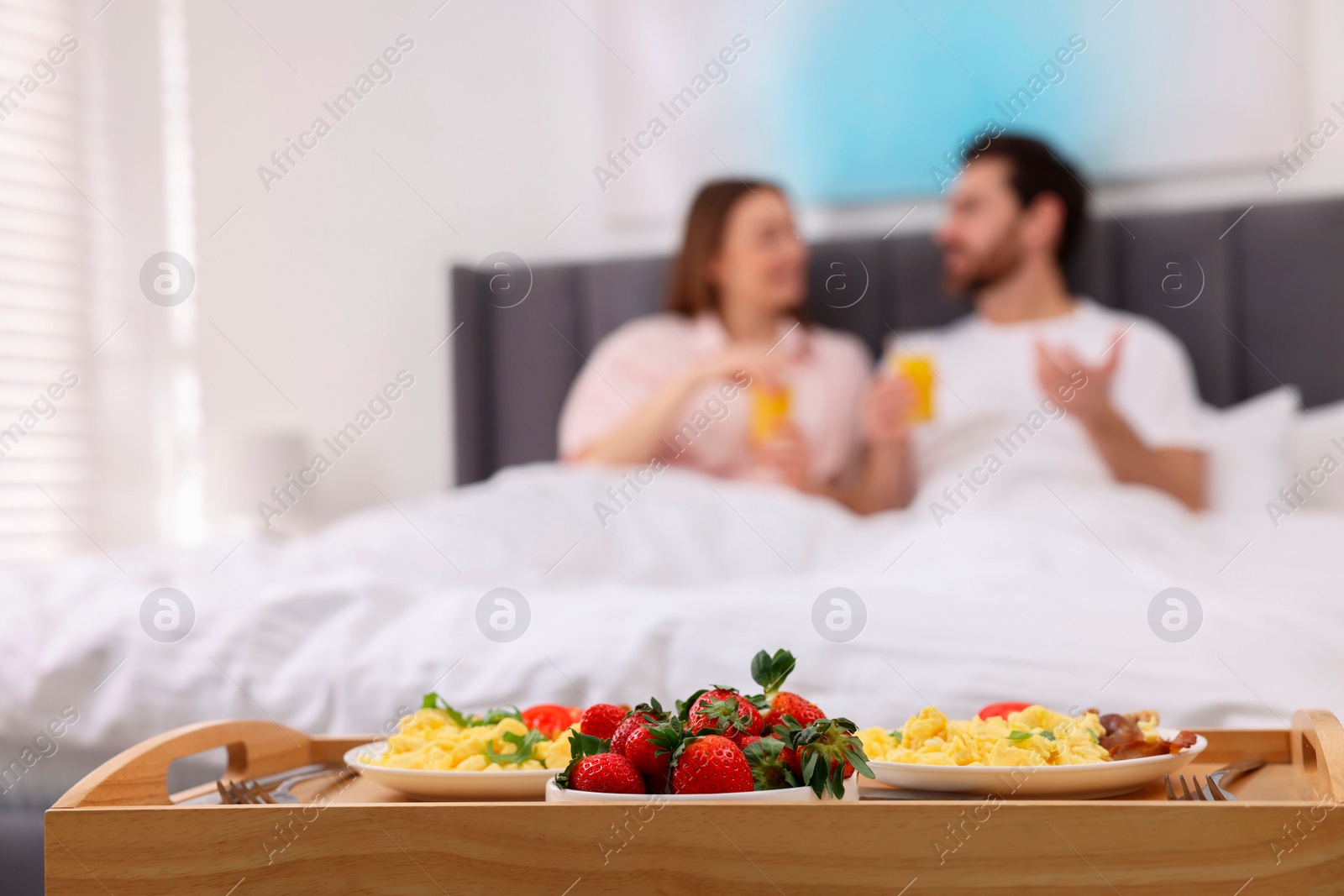 Photo of Tasty breakfast on tray, selective focus. Lovely couple spending time together in bedroom
