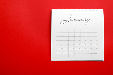 Photo of January calendar on red background, top view. Space for text