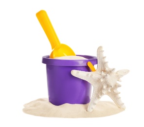 Plastic beach toys and sea star on pile of sand against white background