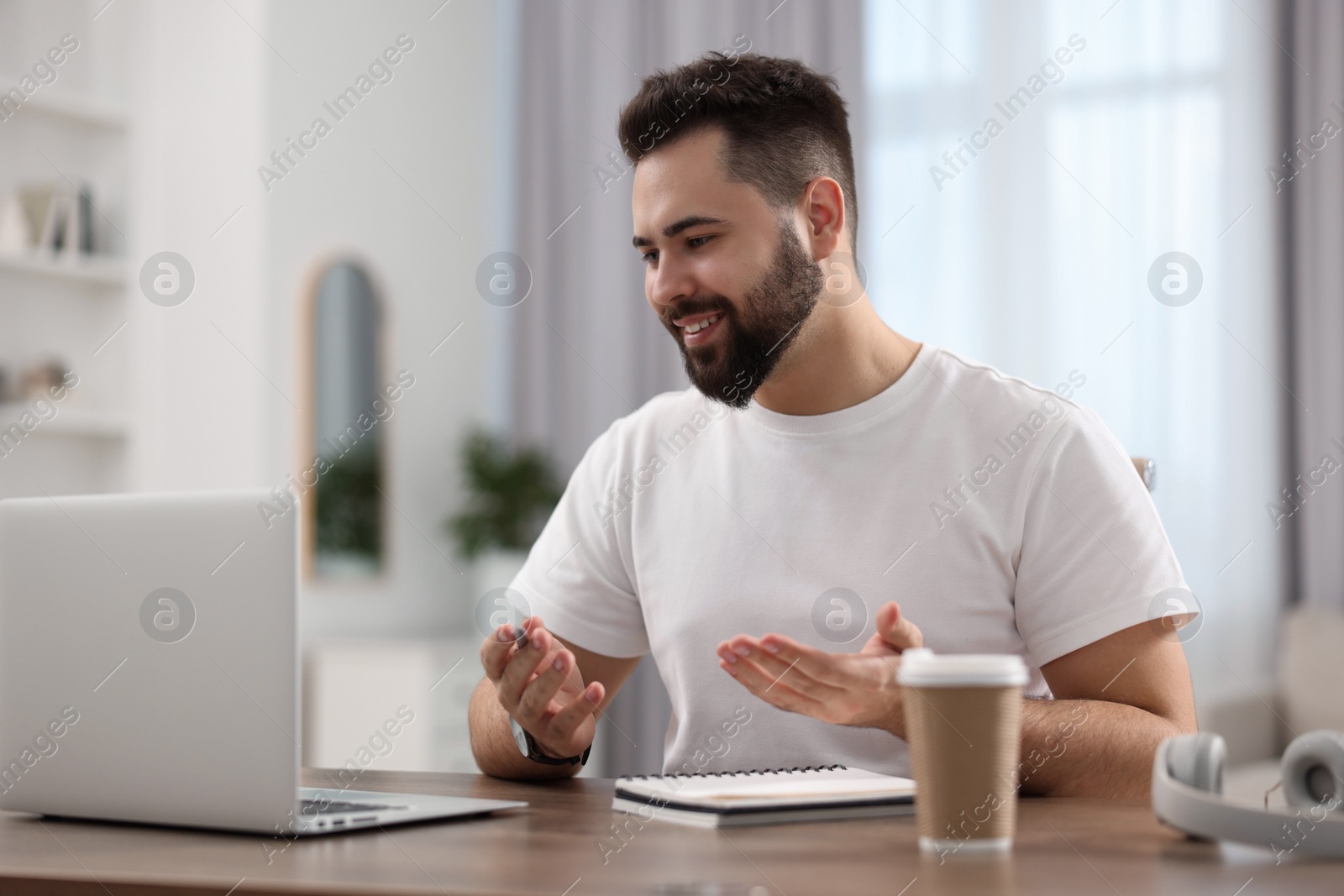 Photo of Young man using video chat during webinar at table in room