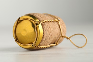Photo of Cork of sparkling wine and muselet cap on white wooden table, closeup