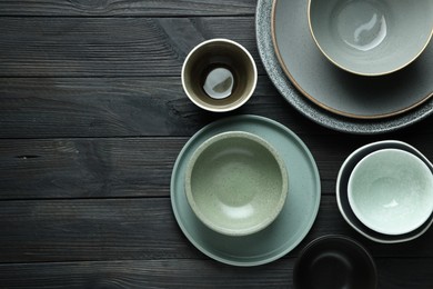 Stylish empty dishware on black wooden table, flat lay. Space for text