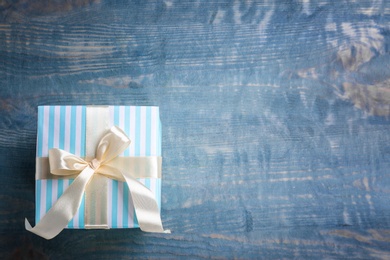 Elegant gift box with bow on wooden background, top view