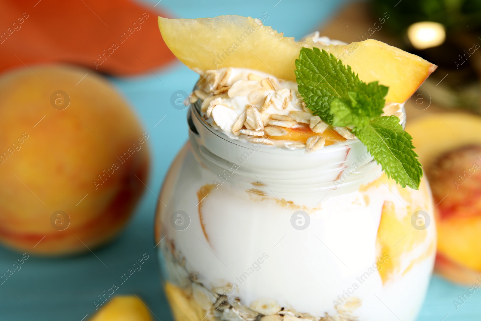 Photo of Tasty peach dessert with yogurt and granola on light blue wooden table, closeup