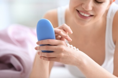 Young woman applying hand cream at home, closeup