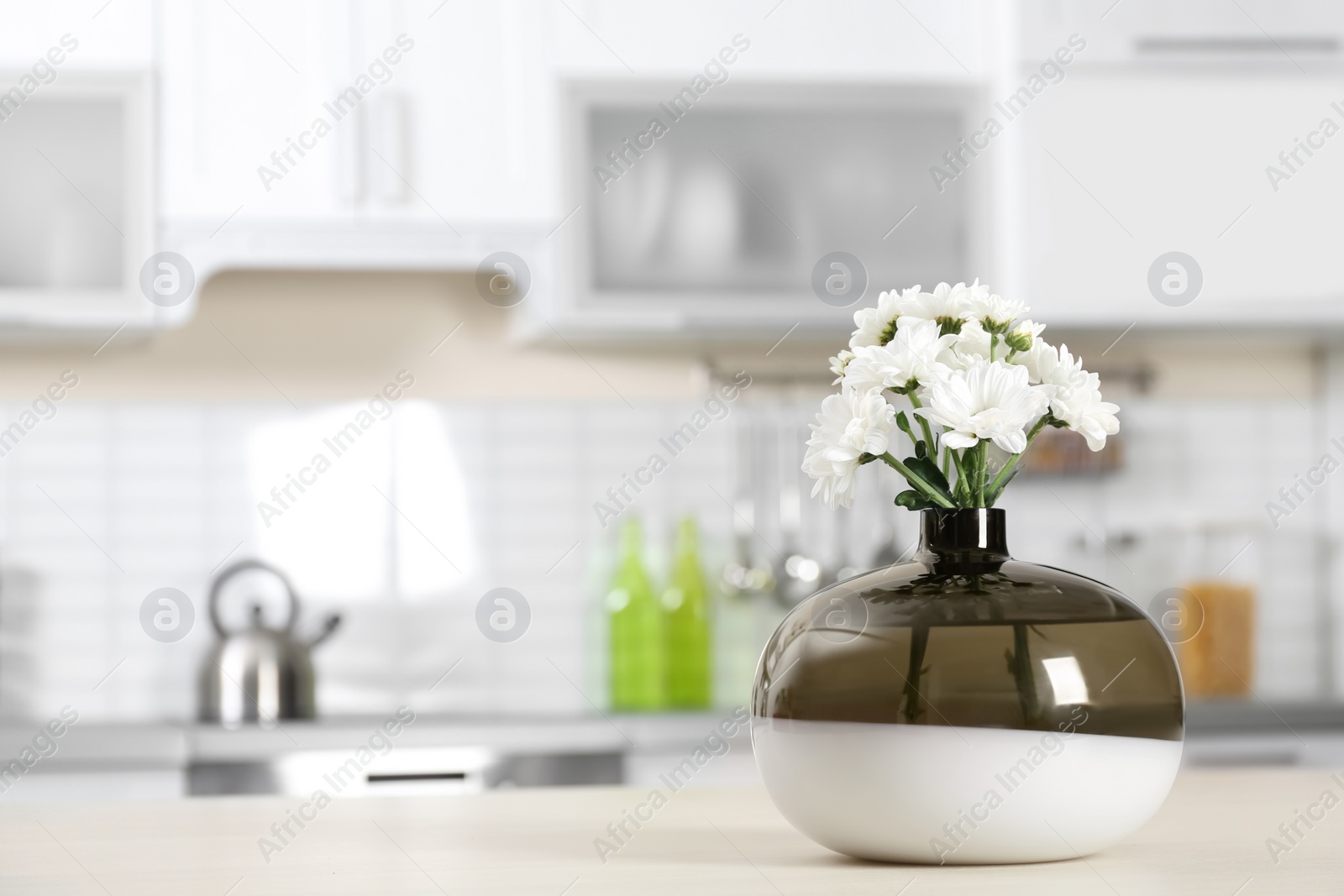 Photo of Vase with beautiful flowers on table in kitchen interior. Space for text