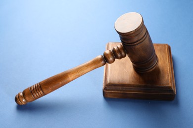 Photo of Wooden gavel and sound block on blue table, closeup