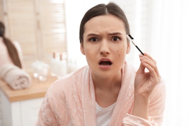 Photo of Beautiful woman with fallen eyelashes and cosmetic brush indoors