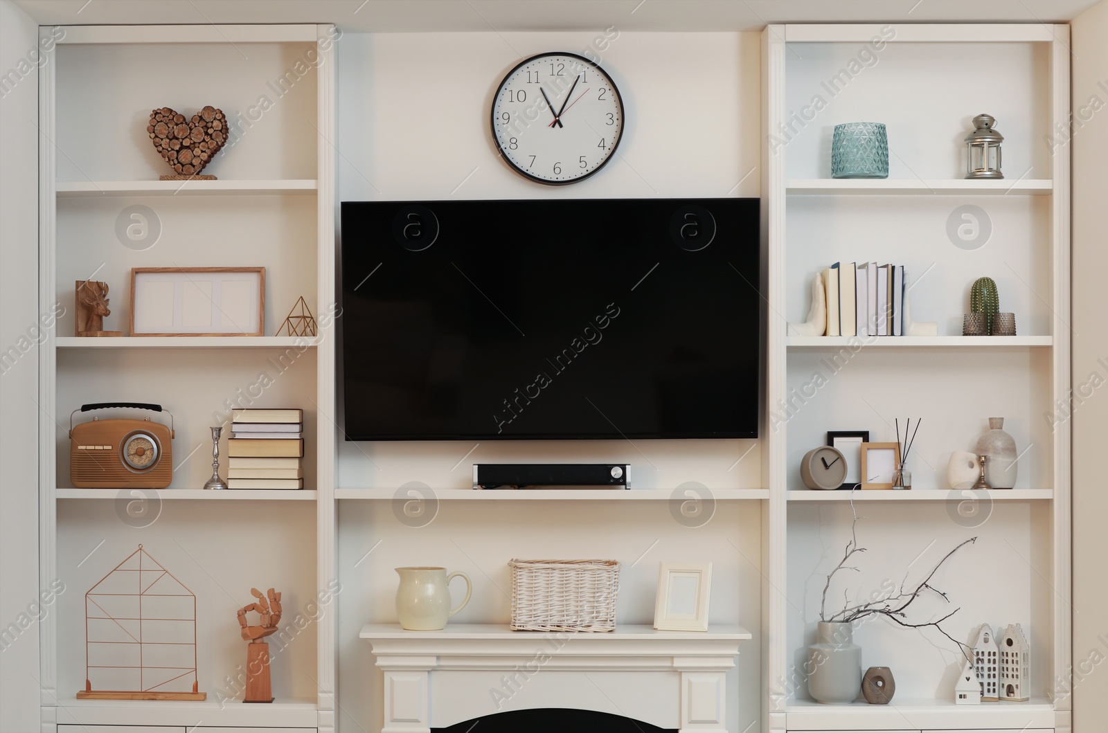 Photo of Stylish shelves with different decor elements and TV set in living room. Interior design