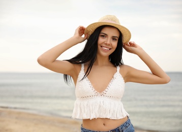 Beautiful young woman with hat on beach