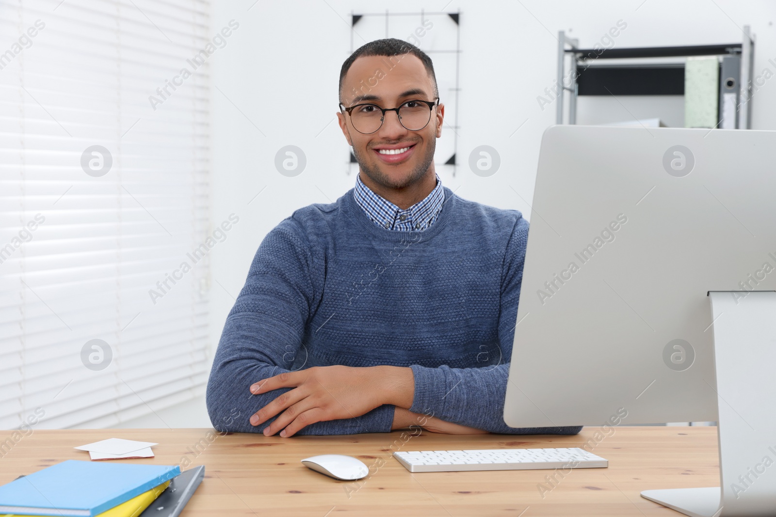 Photo of Happy young intern working at table in modern office