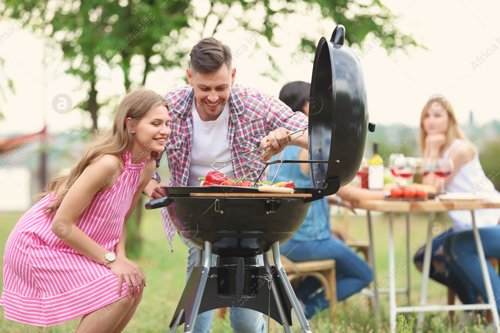 Photo of Young people having barbecue with modern grill outdoors