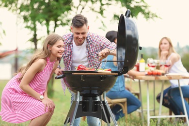 Photo of Young people having barbecue with modern grill outdoors