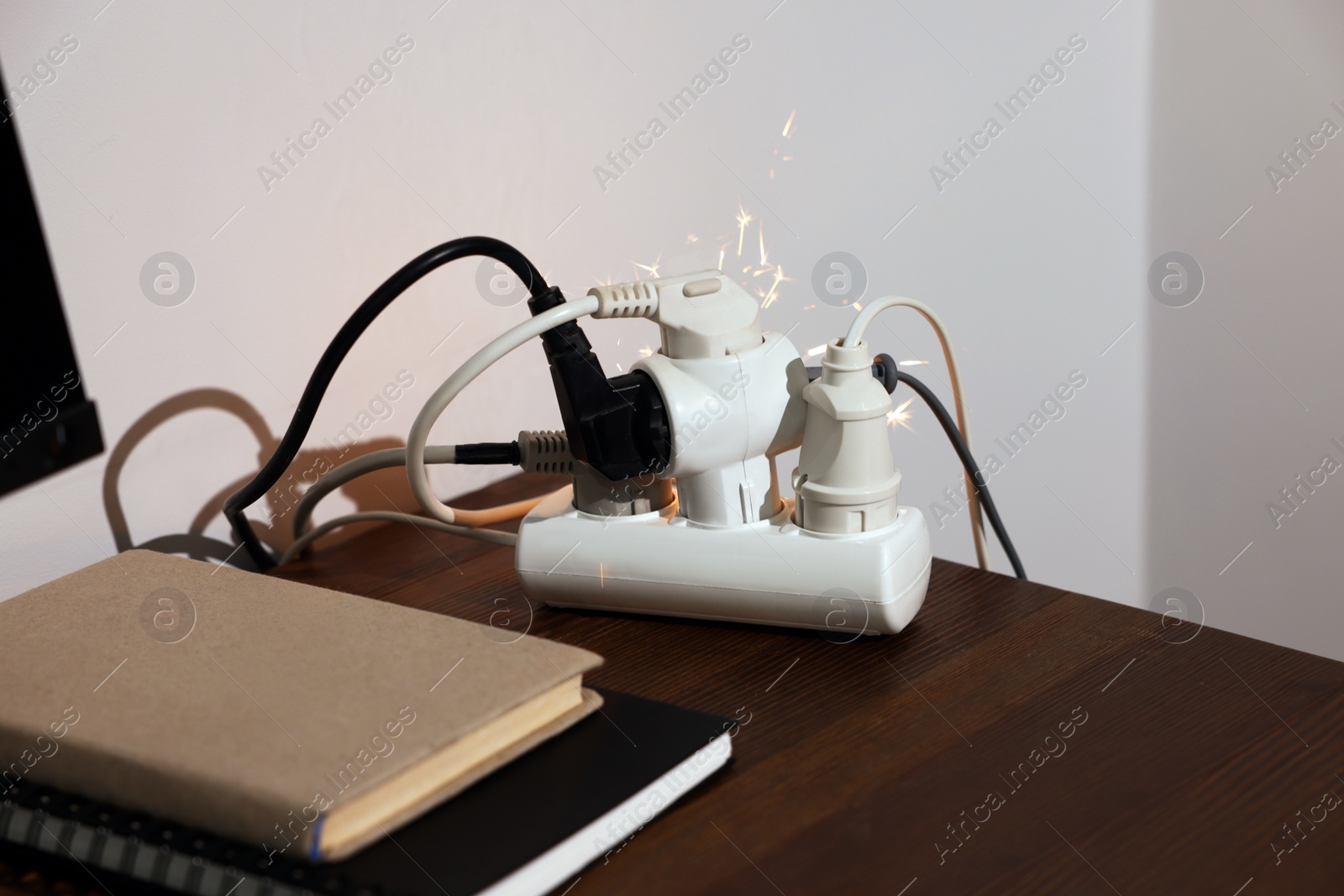 Photo of Inflamed plug in power strip indoors on wooden table. Electrical short circuit