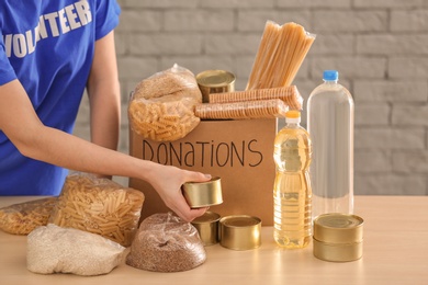 Volunteer collecting food into donation box indoors