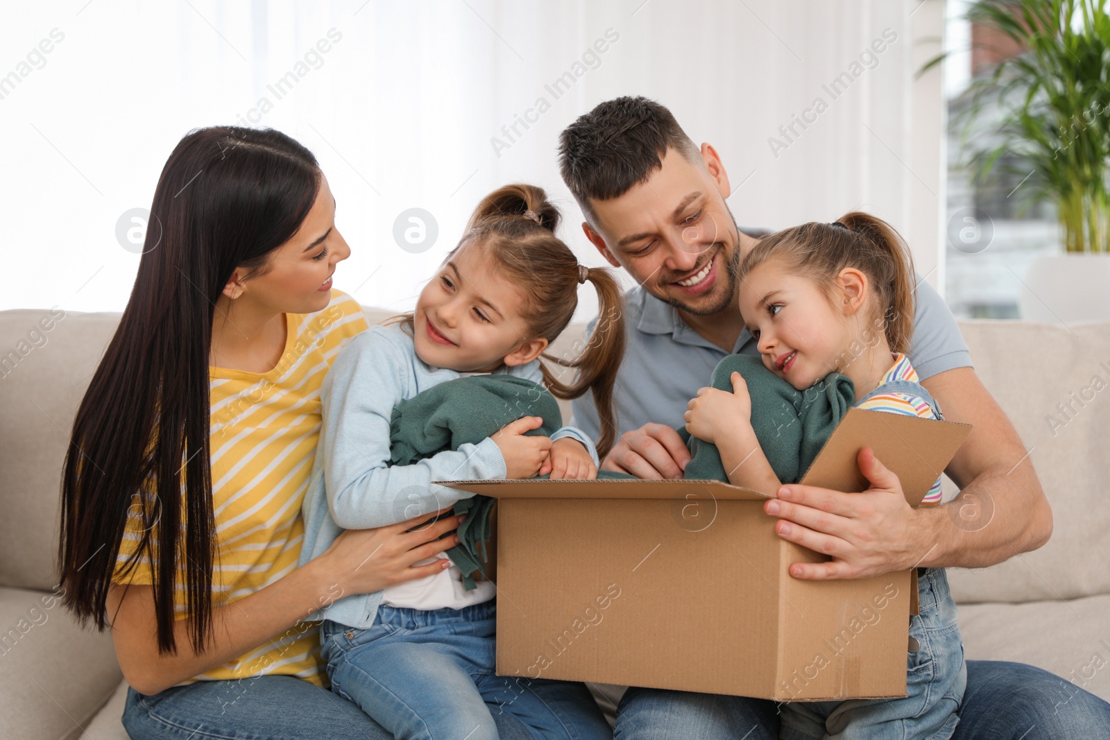 Photo of Happy family unpacking moving box at their new house