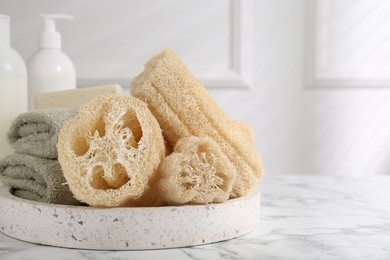 Photo of Loofah sponges, towels and soap on white marble table, space for text