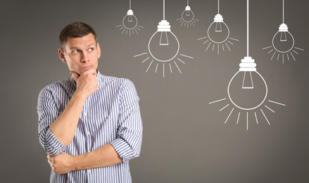 Image of Lightbulbs illustration and thoughtful man in casual outfit on grey background. Business idea