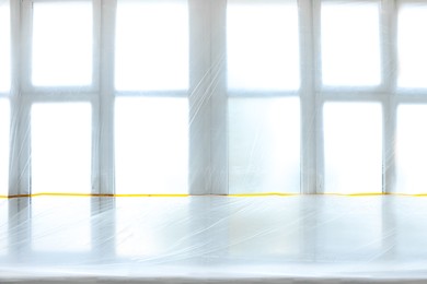 Photo of Window covered with plastic film and insulation tape indoors