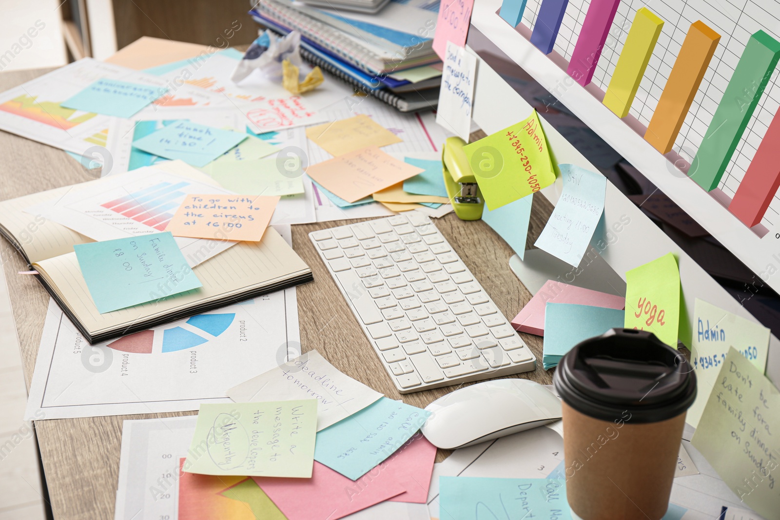 Photo of Computer, notes and office stationery in mess on desk. Overwhelmed with work