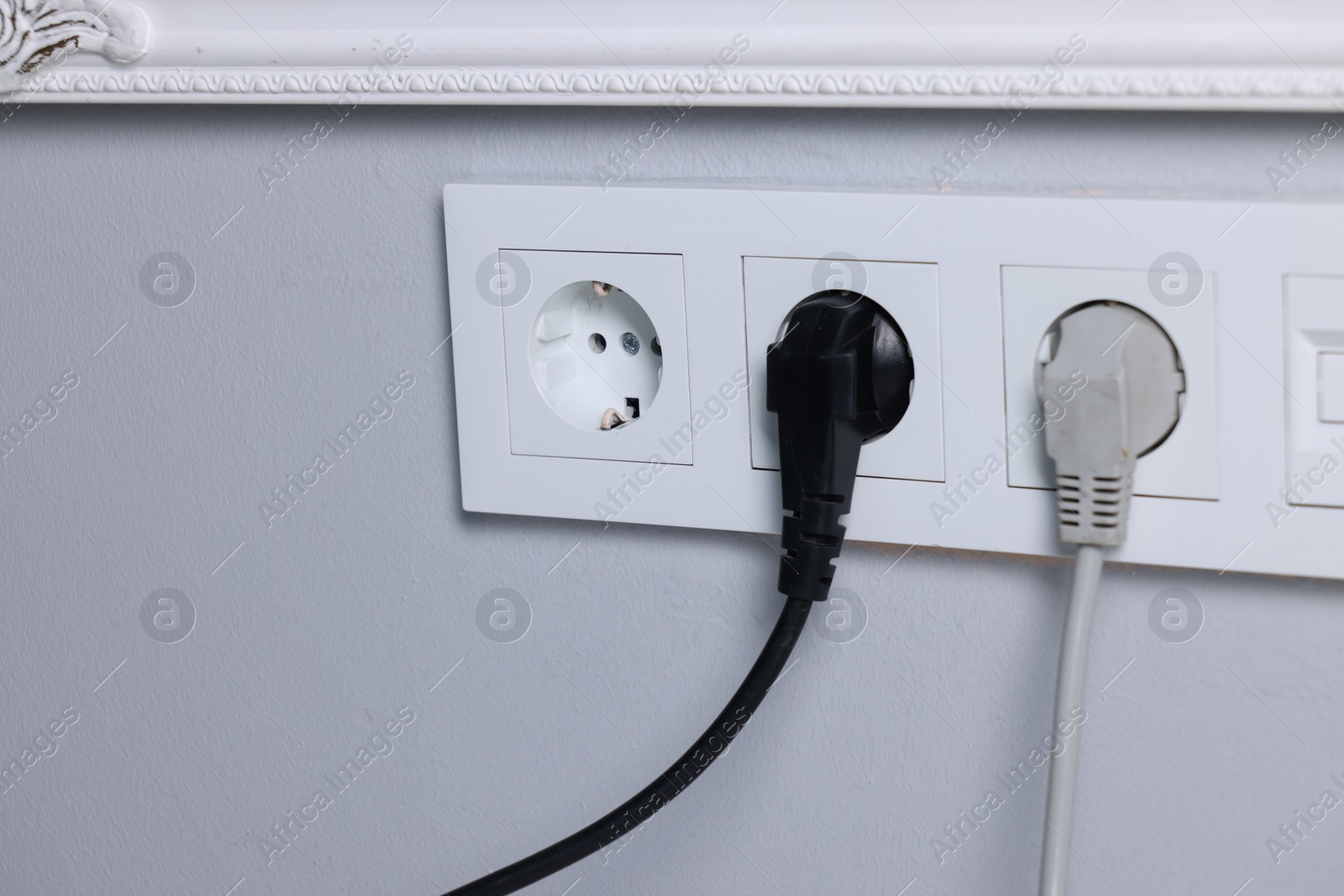 Photo of Power sockets and electric plugs on grey wall, closeup