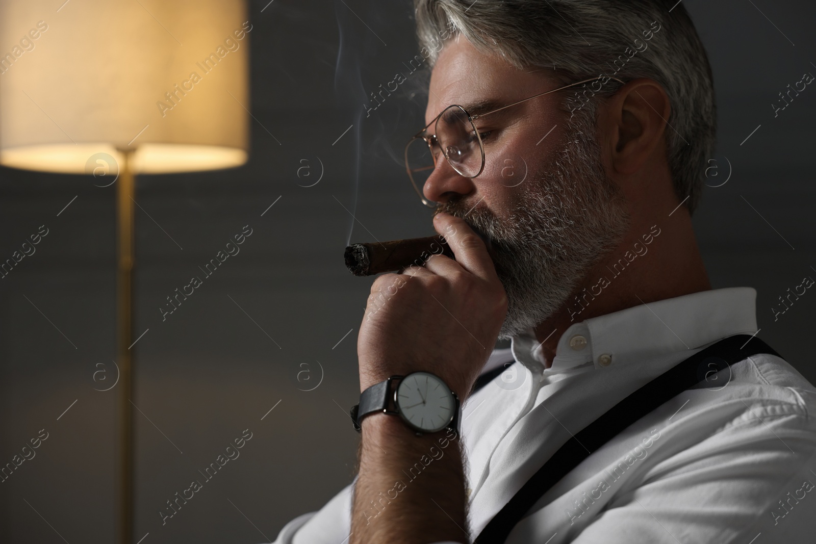 Photo of Bearded man smoking cigar at home. Space for text