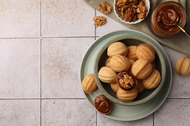 Delicious nut shaped cookies with boiled condensed milk on light textured table, flat lay. Space for text
