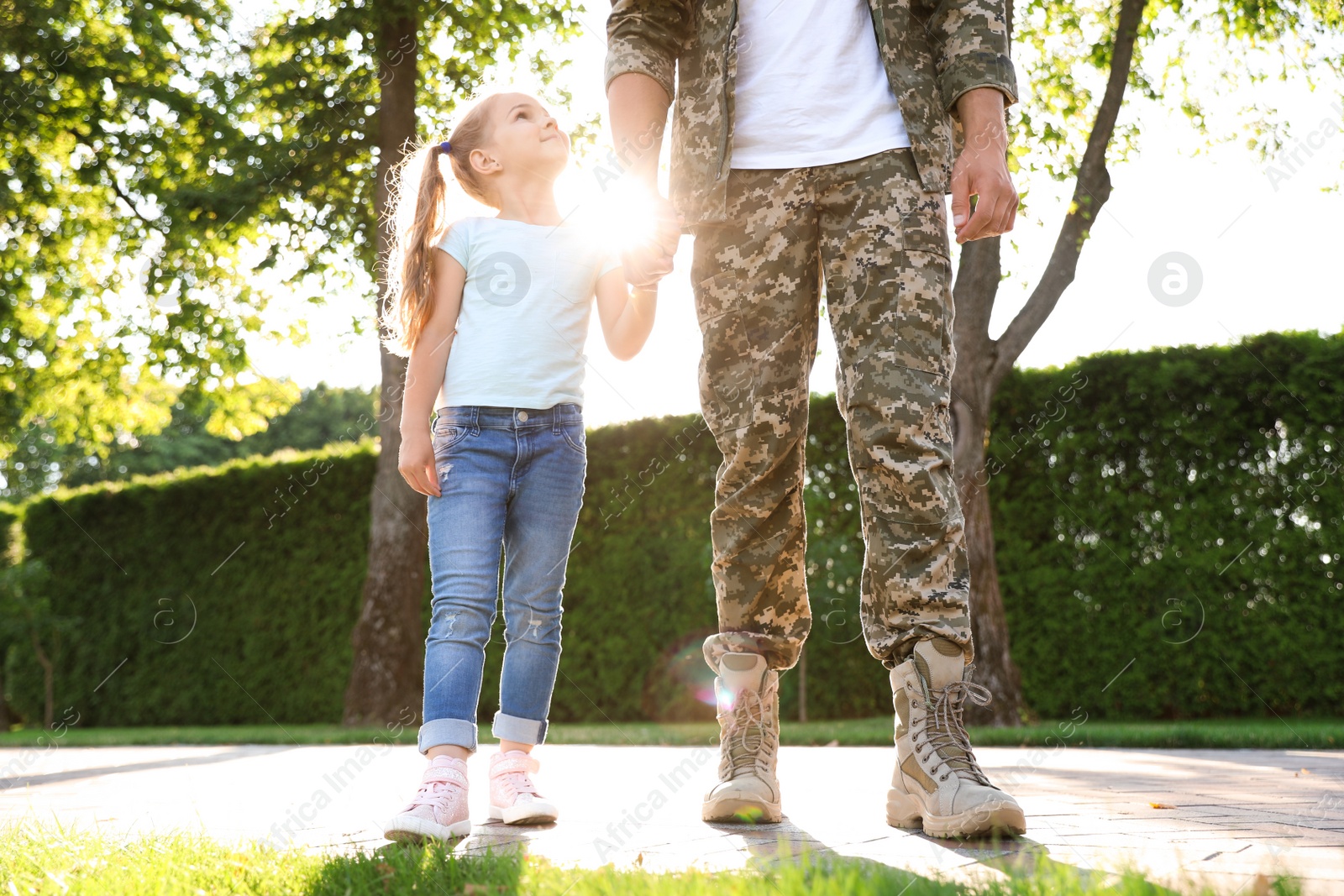 Photo of Father in military uniform walking with his daughter at sunny park