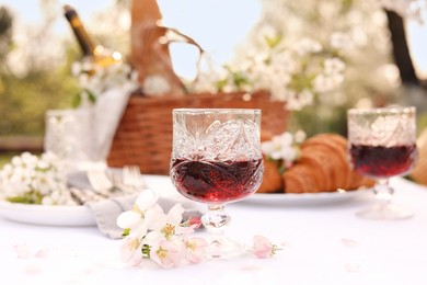 Stylish table setting with beautiful spring flowers, wine and croissants in garden