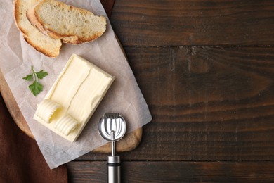 Photo of Tasty butter, slices of bread and spoon on wooden table, top view. Space for text