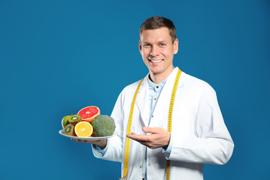 Photo of Nutritionist with healthy products on blue background