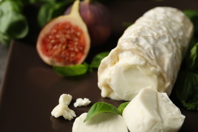 Photo of Delicious goat cheese with figs and basil on plate, closeup