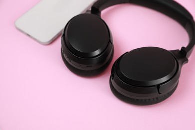 Photo of Modern wireless headphones and smartphone on pink background, closeup