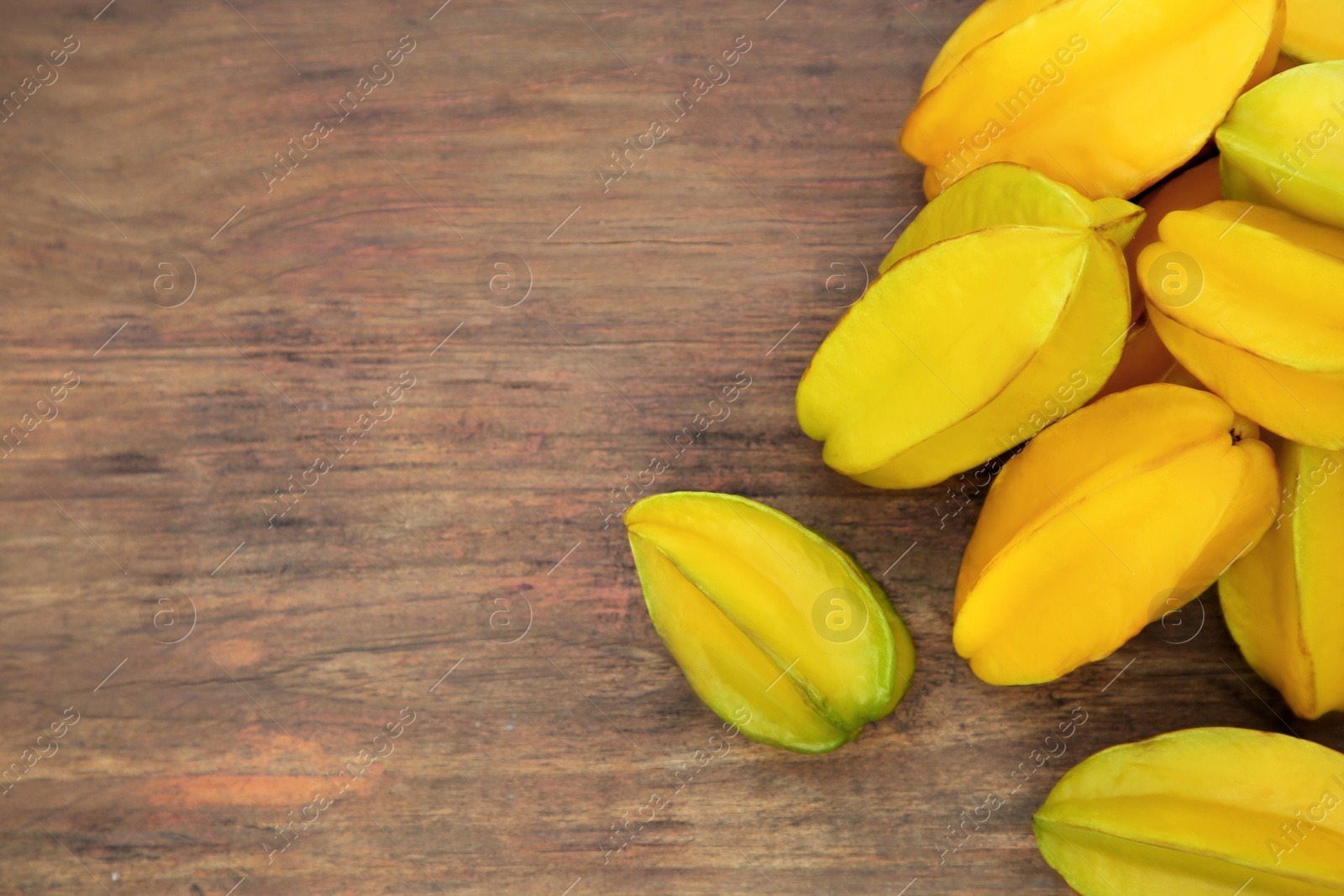 Photo of Delicious ripe carambolas on wooden table, flat lay. Space for text