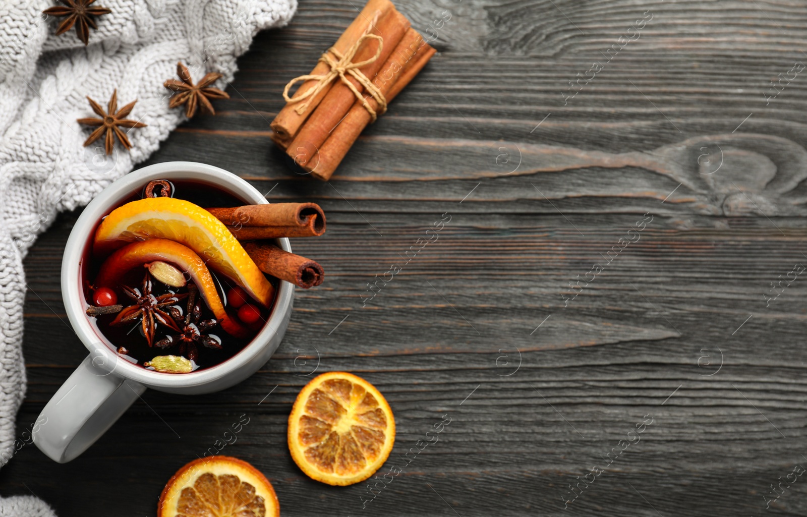 Photo of Cup of tasty mulled wine on black wooden table, flat lay. Space for text