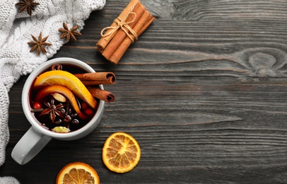 Cup of tasty mulled wine on black wooden table, flat lay. Space for text