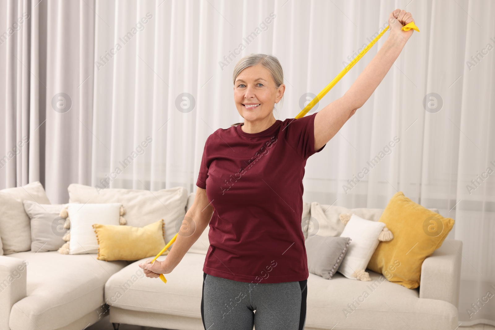 Photo of Senior woman doing exercise with fitness elastic band at home