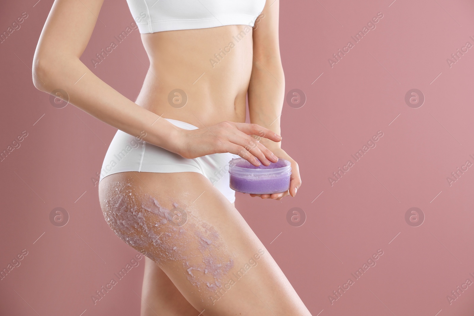 Photo of Young woman applying natural scrub on her body against color background