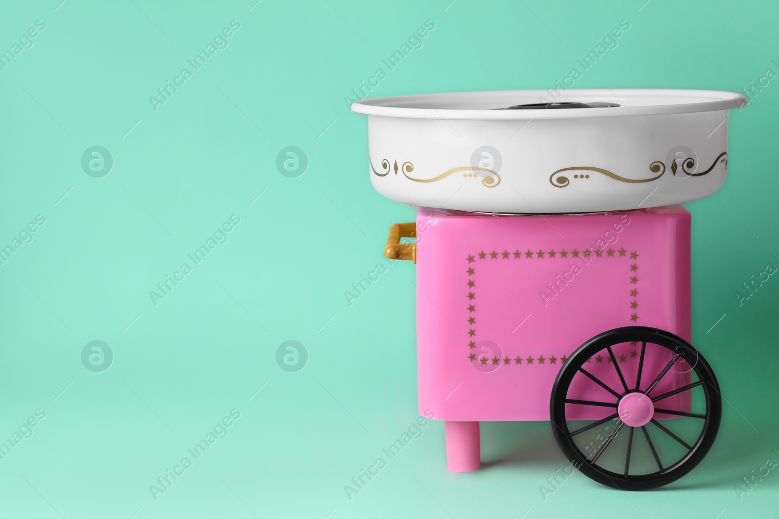 Photo of Portable candy cotton machine on turquoise background, space for text