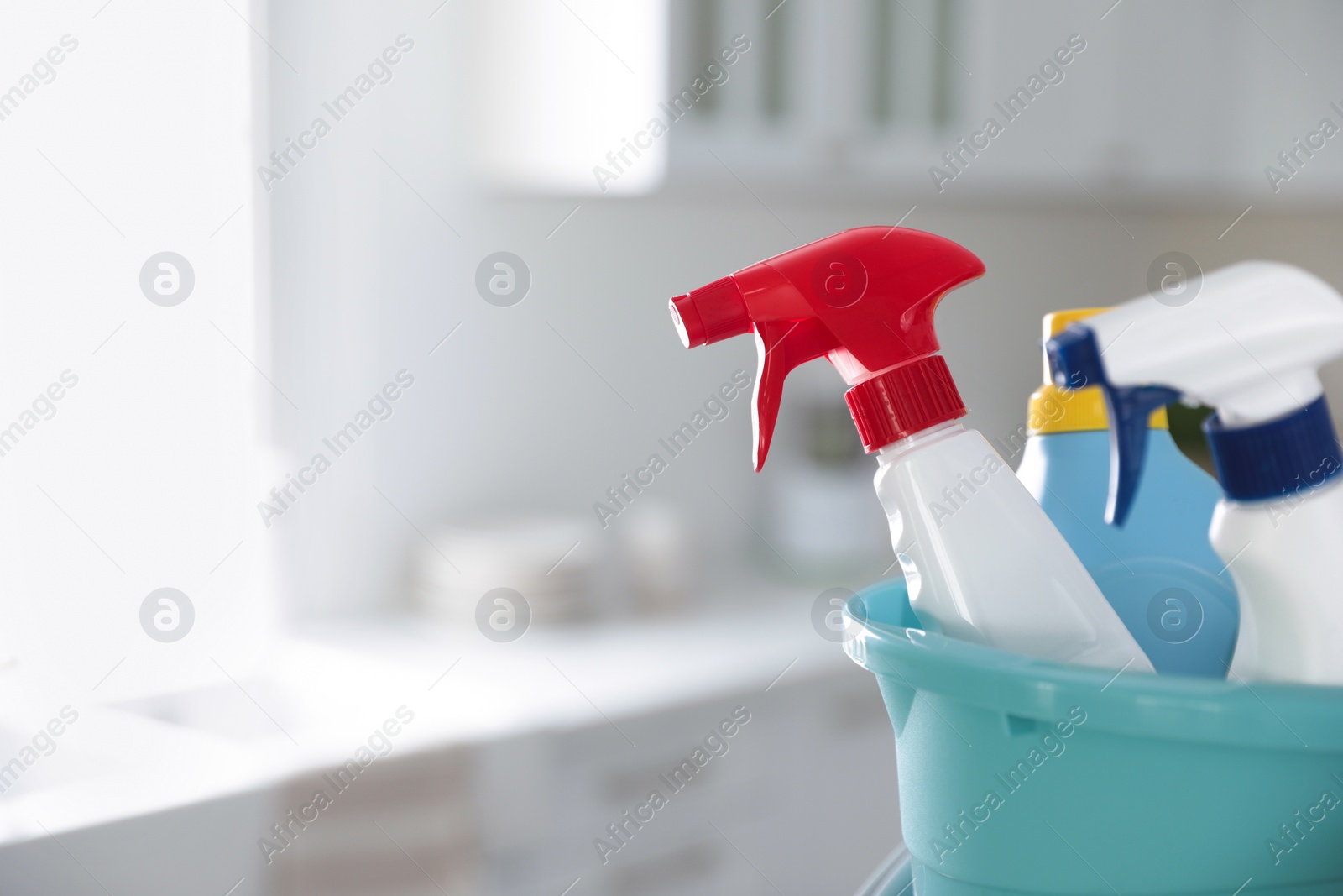 Photo of Plastic bucket with different cleaning supplies in kitchen, closeup. Space for text