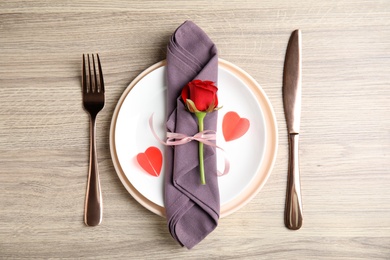 Photo of Beautiful place setting for romantic dinner on wooden table, flat lay. Valentine's day celebration
