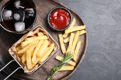 Photo of Tasty french fries, ketchup and soda drink on black table, top view