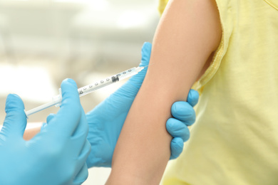 Photo of Doctor vaccinating little child in clinic, closeup