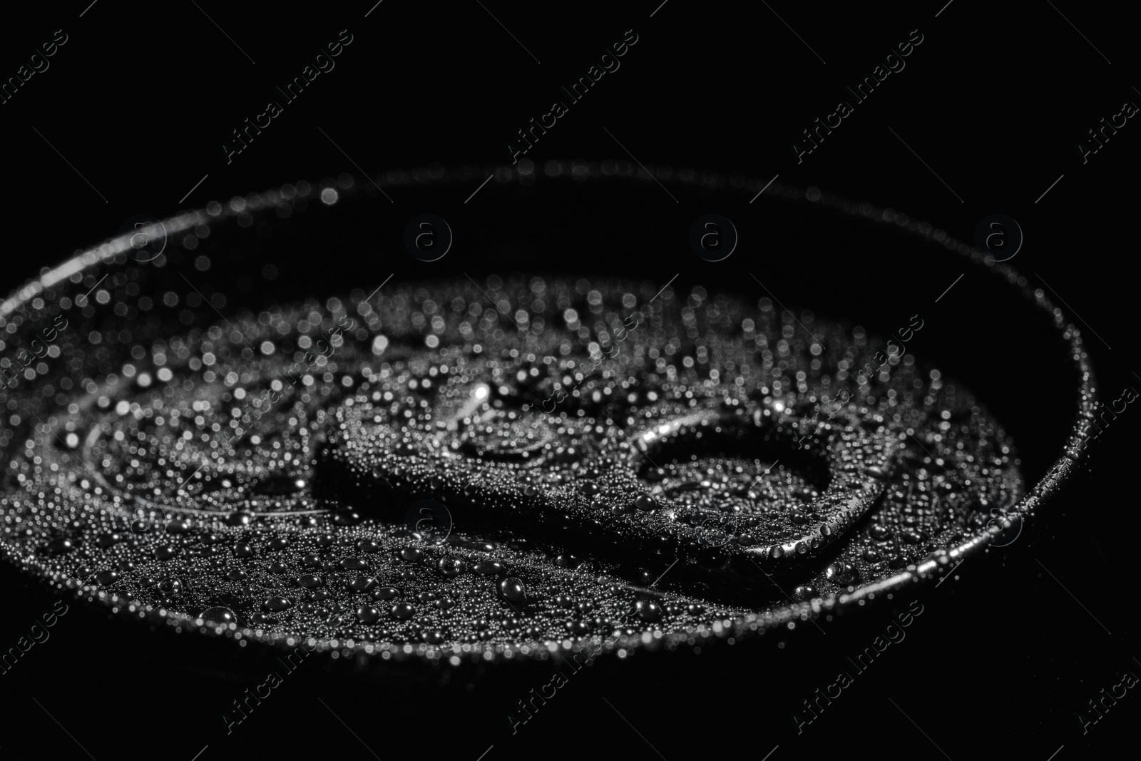 Photo of Aluminum can of beverage covered with water drops on black background, closeup