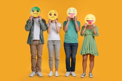 Photo of People covering faces with emoticons on yellow background